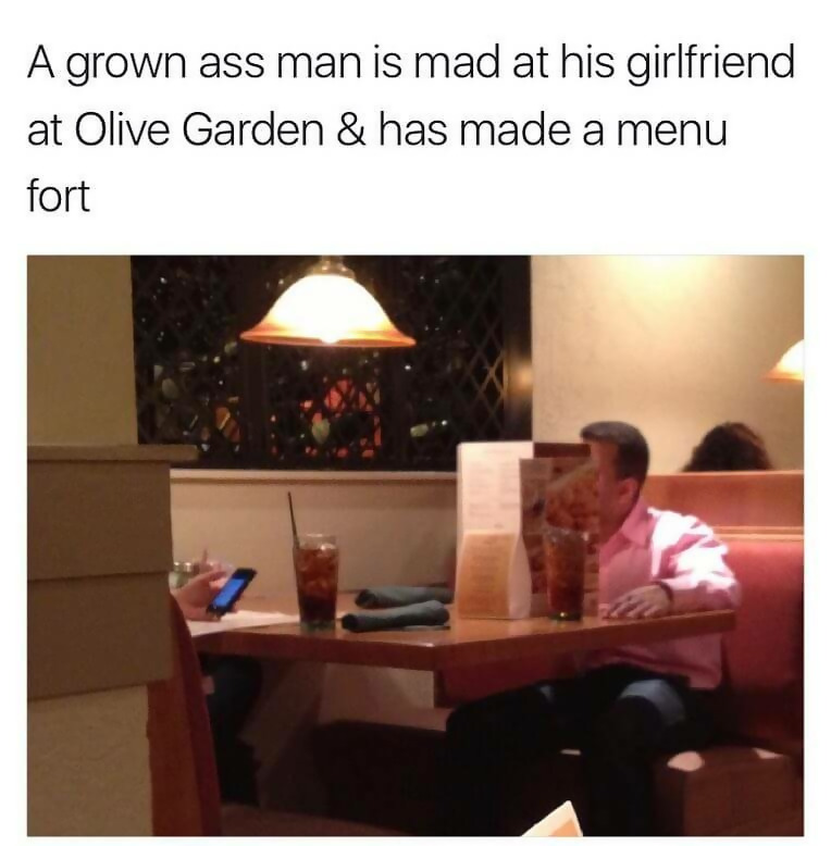 man hiding behind menus at Olive Garden because he is mad at girlfriend